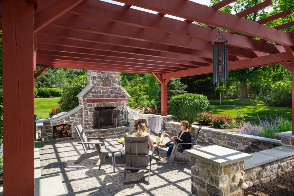 Relaxing beneath a pergola in front of an outdoor fireplace in Center Valley