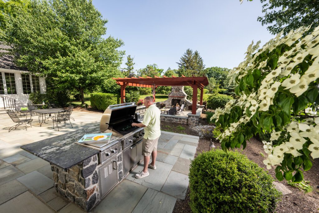 Man grilling on flagstone patio with pergola in the background in Coopersburg