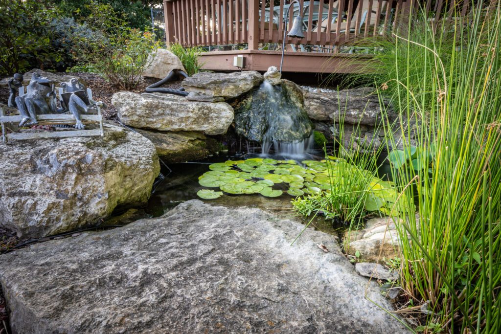 Landscaped fishpond with waterfall coming from boulders in Zionsville