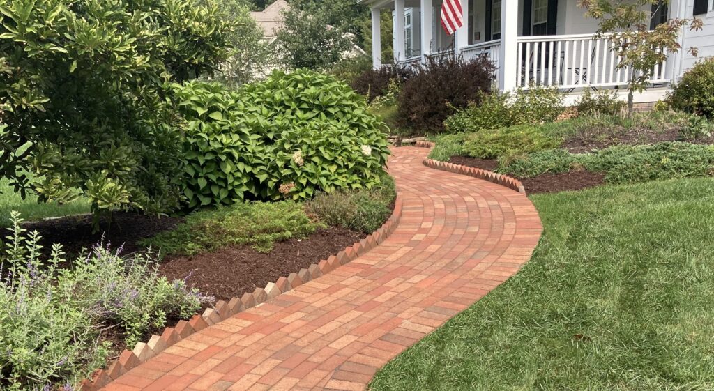 Brick walkway with mulch beds and plants alongside it in Orefield